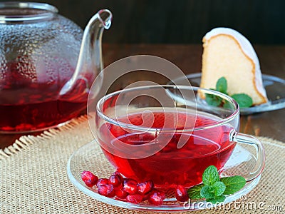 Cup of pomegranate tea with mint and tea pot with a piece of cake Stock Photo