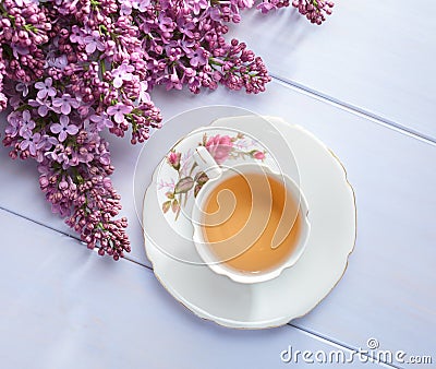 Cup of tea and branches of blooming lilac on wooden table Stock Photo