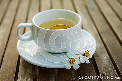 Cup of tea & Couple of wild daisy flower on a ceramic dish on wooden table Stock Photo