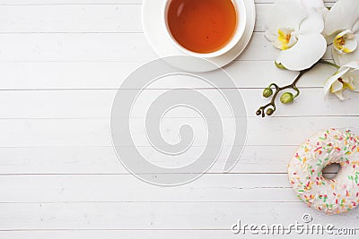 Cup of tea and donuts, white orchid on white table with copy space. Flat lay, top view Stock Photo