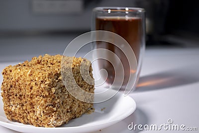 Cup of tea in a double-botoom glass and piece of cake on white table in gray kitchen Stock Photo