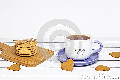 A cup of tea with the inscription good luck and a stack of crispy cookies on a wooden cutting board Stock Photo