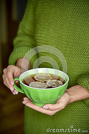 Cup of tea with lemon in hand, yellow autumn leaf.Warm drink concept. Stock Photo