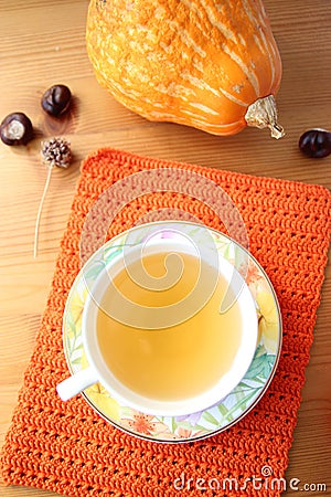 A cup of tea on orange knitted mat and pumpkin on wood table Stock Photo