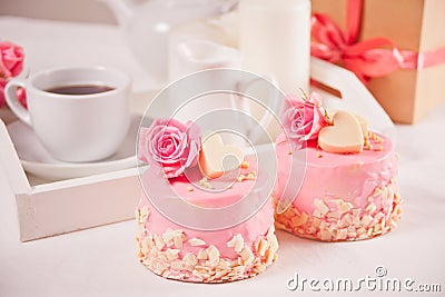 A cup of tea, pink roses, gift box and small cakes on the white table. Romantic concept Stock Photo