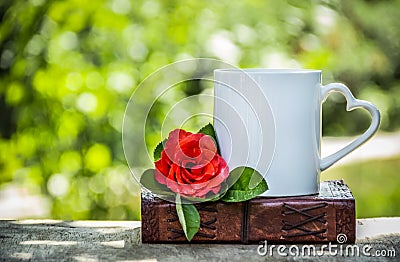 Cup of tea and a red rose. Coffee in the garden. Romantic breakfast. White mug with a heart Stock Photo