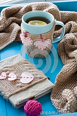 A cup of tea in sweater, old notebook with hearts of felt, beige Stock Photo