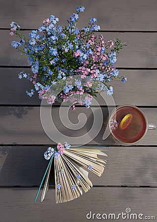 Cup of tea on the table, a book and a bouquet of forget-me-nots Stock Photo