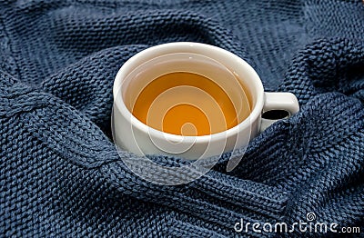 A cup of tea wrapped in a warm, blue sweater Stock Photo