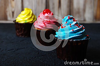 Cupcake cakes yellow, pink, blue on a dark background Stock Photo