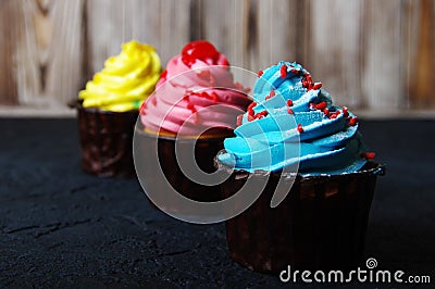 Cupcake cakes yellow, pink, blue on a dark background Stock Photo