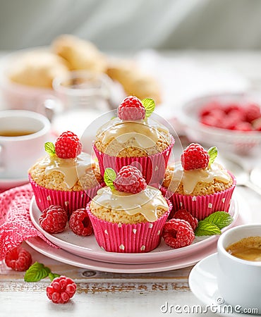 Cupcakes with white chocolate and fresh raspberries on a ceramic plate on a wooden white table, close up. Stock Photo