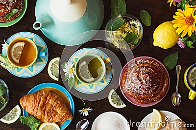 Cups of herbal tea with lemon and mint leaves, ginger root and croissant on the wooden background Stock Photo