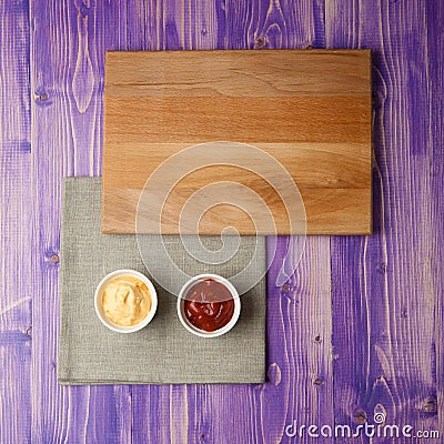 Cups with ketchup and cheese on napkin made from canvas on a wooden table Stock Photo