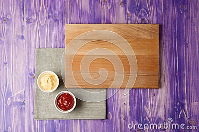 Cups with ketchup and cheese on napkin made from canvas on a wooden table Stock Photo