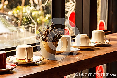 Cups on the shelf in warm sunlight in Romantic Atmosphere of Coffee Shop Stock Photo