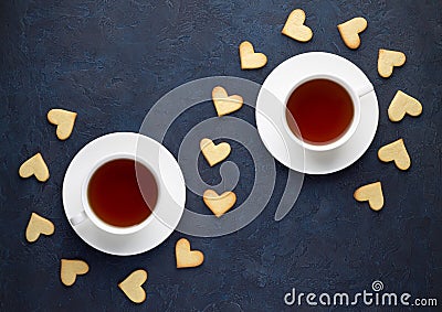 Cups of tea and shaped heart cookies on stone background. Stock Photo