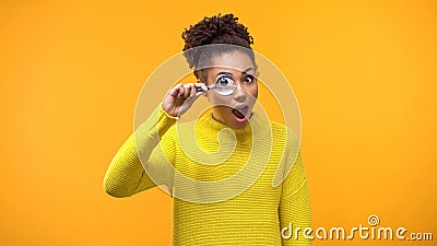 Curious afro-american woman looking magnifying glass, having fun, surprise Stock Photo