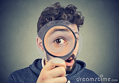 Curious amazed man looking through a magnifying glass Stock Photo