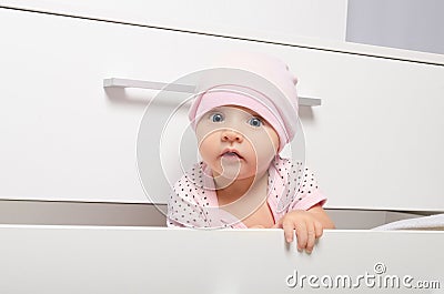 Curious baby looking out of the chest of drawers Stock Photo