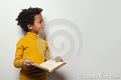 Curious black child boy reading a book on white background Stock Photo