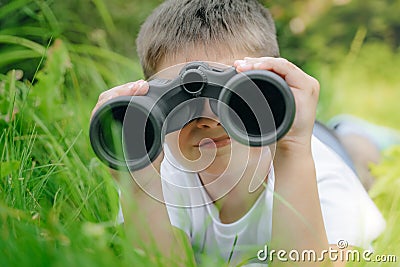 Curious boy looks for wildlife through binoculars in the park. Exploring the world, bird watching. Outdoor activities. boy looking Stock Photo