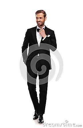 Curious businessman in black suit stands with hand in pocket Stock Photo