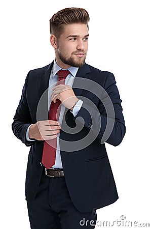 Curious businessman fixing his tie and looking over his shoulder Stock Photo