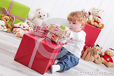 Curious child: young girl opening Christmas present with teddy b Stock Photo