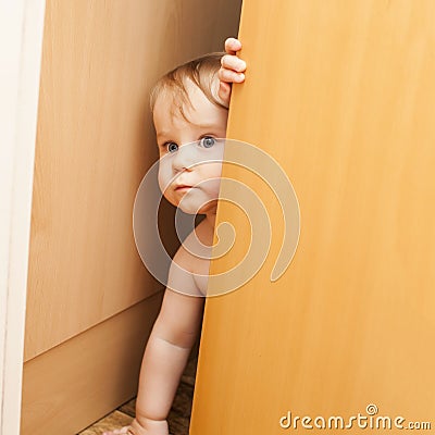 Curious cute baby boy looking through ajar door Stock Photo