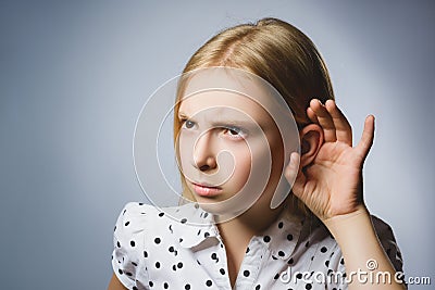 Curious Disappointed girl listens. Closeup portrait child hearing something, parents talk, hand to ear gesture isolated Stock Photo