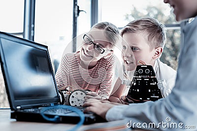 Curious kids looking at laptop while working on robots Stock Photo