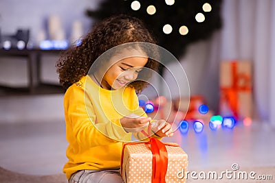 Curious little black girl opening gift box on Christmas Eve Stock Photo