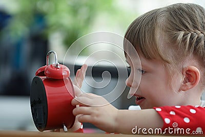 Curious little pretty girl explore red clock touch dial with finger Stock Photo