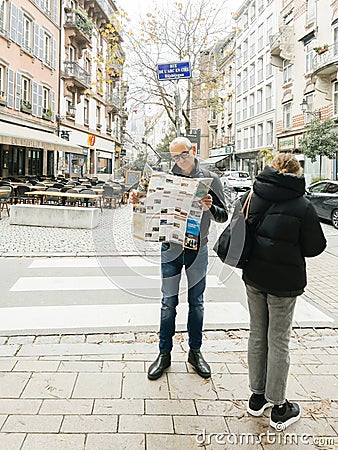 Curious male tourist reading a traveler tourist sightseeing map of Strasbourg in Editorial Stock Photo