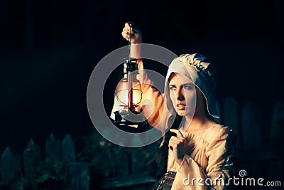 Curious Medieval Woman with Vintage Lantern Outside at Night Stock Photo