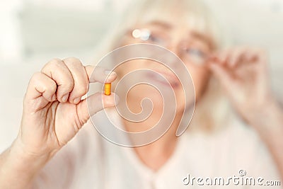 Curious retired woman viewing pill at home Stock Photo