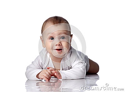 Curious shocked infant baby boy toddler in diaper and white bodysuit is lying on floor on his stomach crawling Stock Photo