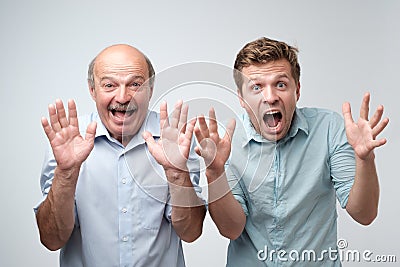 Curious shocked men, standing in casual shirts, isolated on pure background with wonderment. Stock Photo