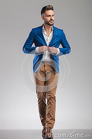 Curious smart casual man buttons suit while walking forward Stock Photo