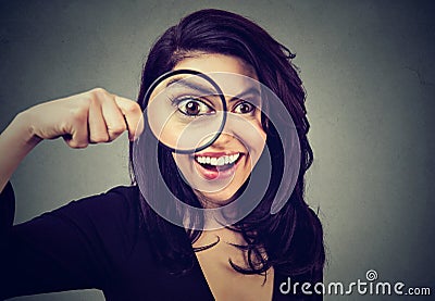 Curious surprised young woman looking through a magnifying glass Stock Photo