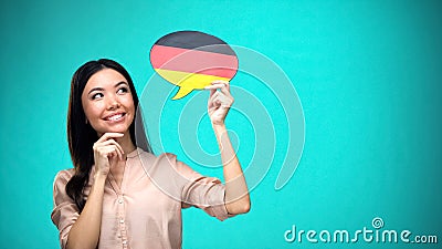 Curious woman holding German flag sign, learning language, education abroad Stock Photo