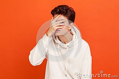 Curious young man in casual sweatshirt with hood looking through fingers, scared teenager looking with apprehension, spying Stock Photo