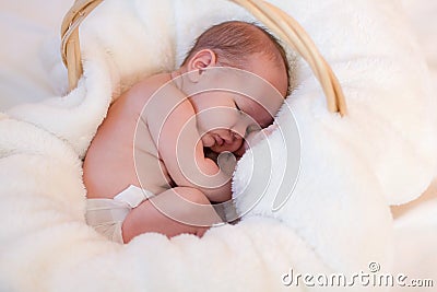 Curled up infant in basket Stock Photo