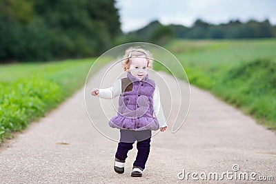 Curly baby girl on country road on cold day Stock Photo