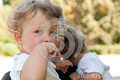 Curly child holds her hand to her mouth at the hands of men Stock Photo