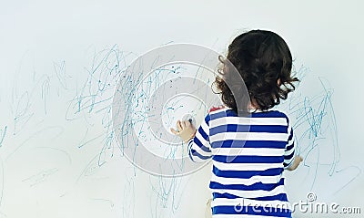 Curly cute little baby girl drawing with crayon color on the wall. Works of child Stock Photo