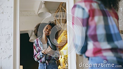 Curly funny african american girl dancing and singing with hair dryer in front of mirror at home Stock Photo