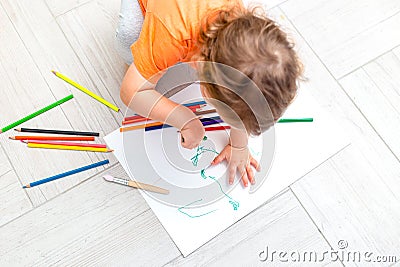 Curly girl draws with pencils on a white sheet of paper at home. Flat lay Stock Photo