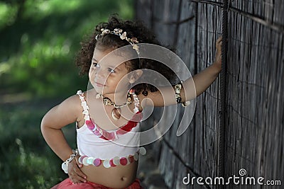Curly girl in a pink dress with shell decorations on the nature Stock Photo